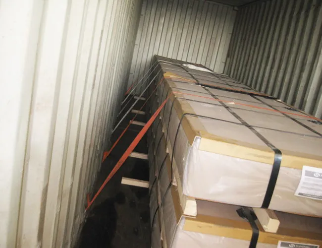 Professional forklift loading heavy aluminum plates into maritime shipping container